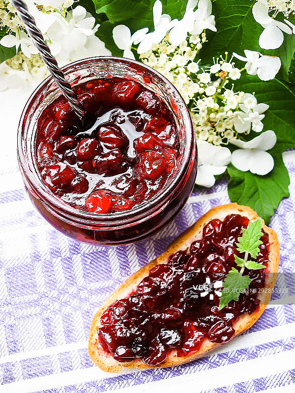 罐装蔓越莓酱或酱汁，以及一块涂有蔓越莓酱的早餐面包图片素材