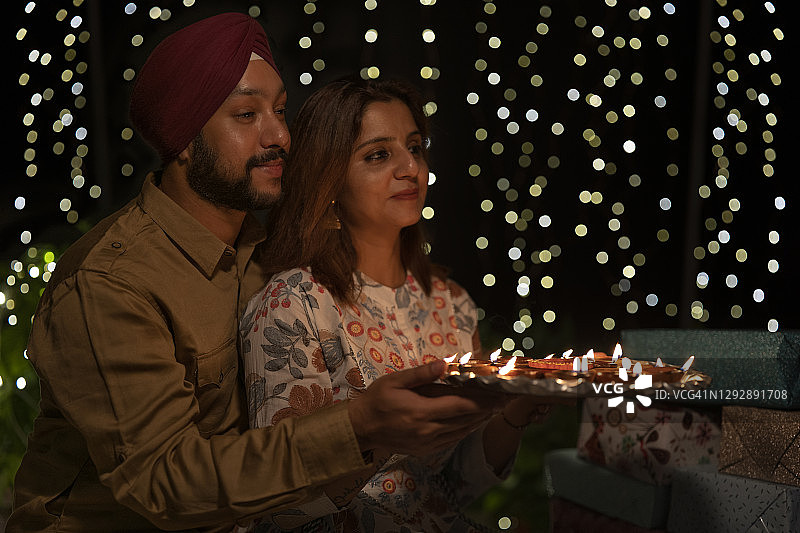 锡克教男女手捧灯盏，以礼物和灯光为背景合影图片素材