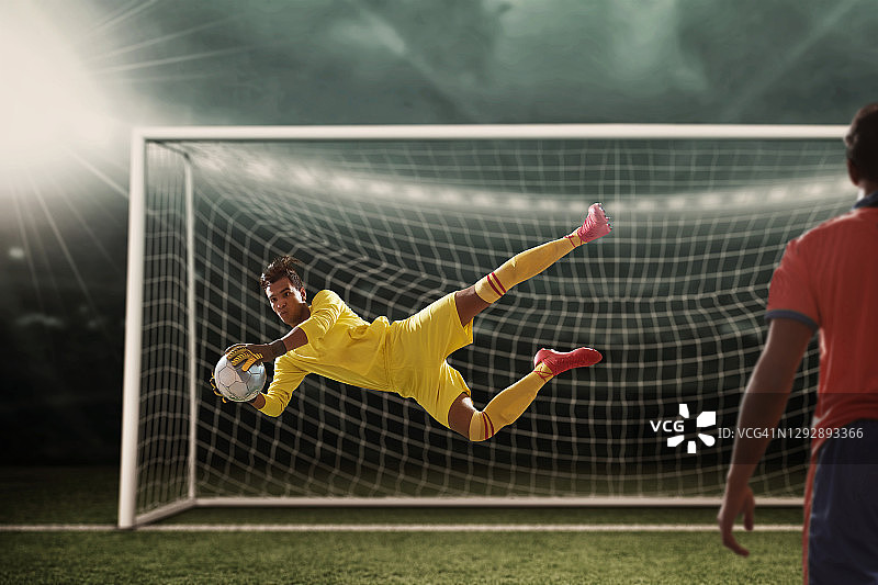 聚光灯下的体育场里，守门员接住了球图片素材