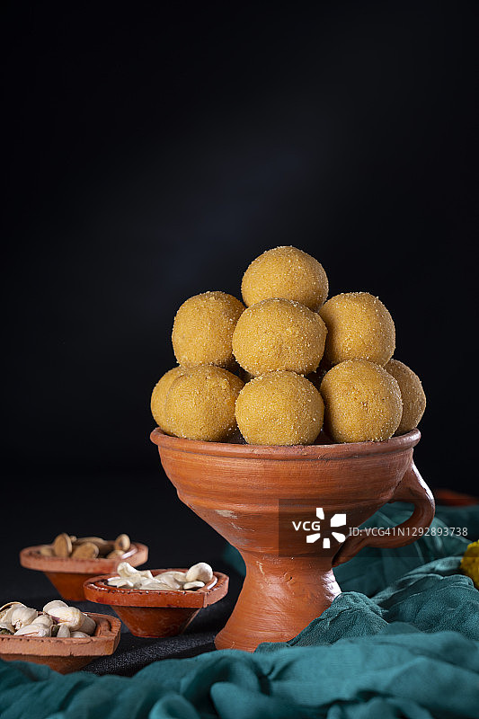 用土制香炉盛放的鹰嘴豆拉杜，旁边放着杏仁和腰果图片素材