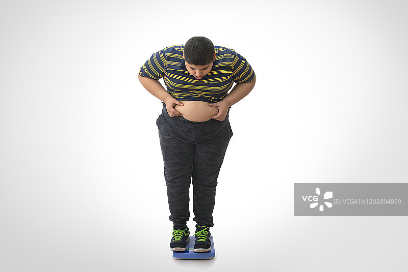 小男孩站在体重秤上查看体重（肥胖）图片素材