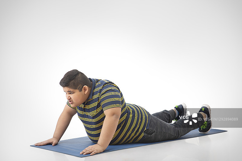 小男孩在瑜伽垫上锻炼图片素材