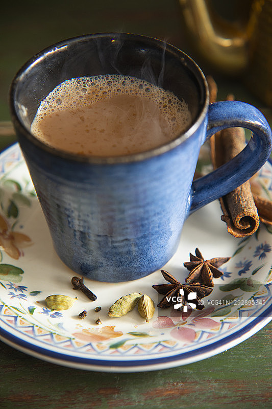 杯子装满热茶，放在茶托上，旁边放着香料图片素材
