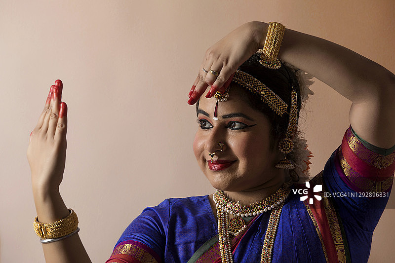 在纯色背景前表演的 Bharatnatyam 舞者图片素材