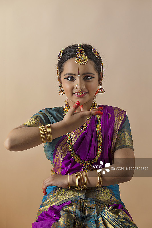 年轻的印度古典舞舞者在纯色背景前优雅微笑图片素材