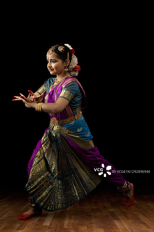 年轻的印度古典舞者在黑暗背景前表演图片素材