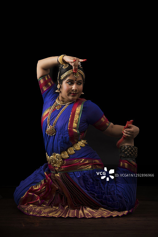 在深色背景下表演的印度古典舞舞者图片素材