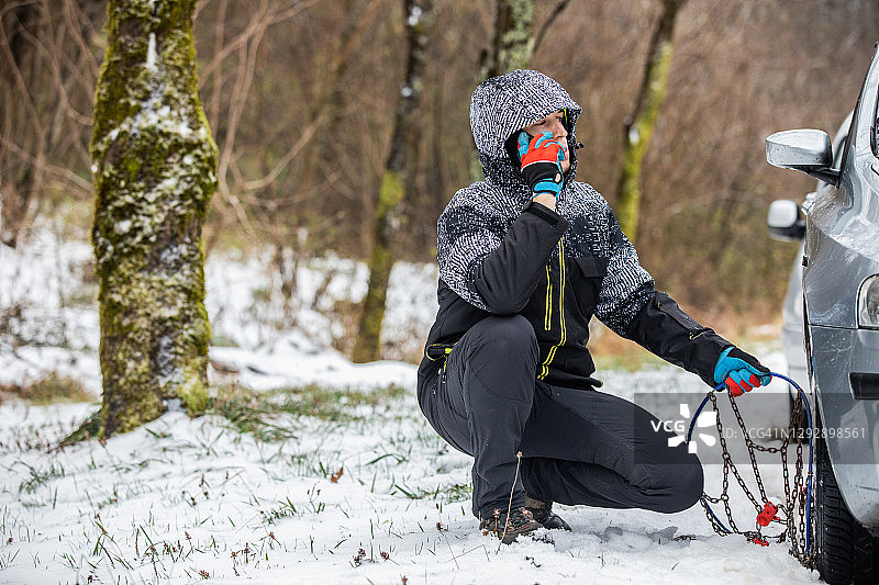 年轻男子在安装轮胎链时用手机交谈图片素材