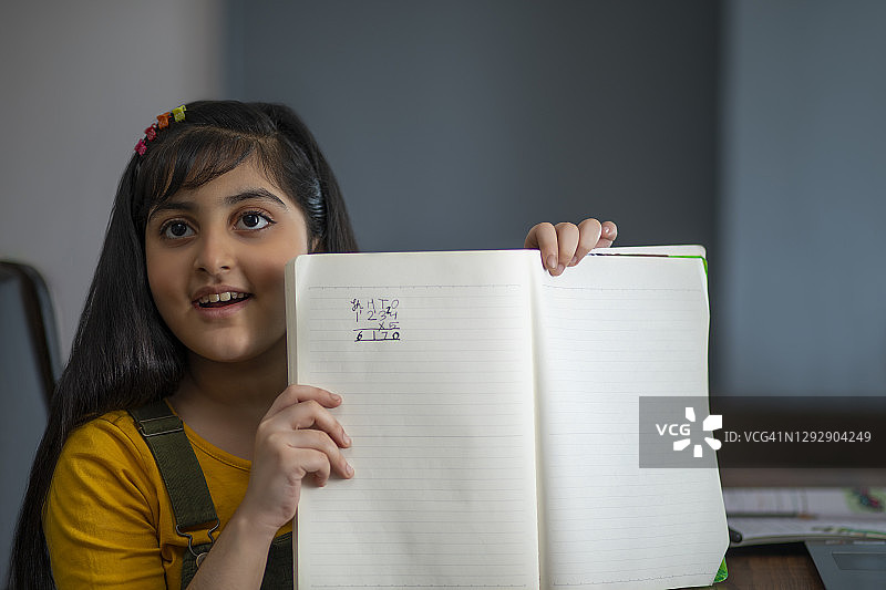 女孩展示她在笔记本中解决的数学题图片素材