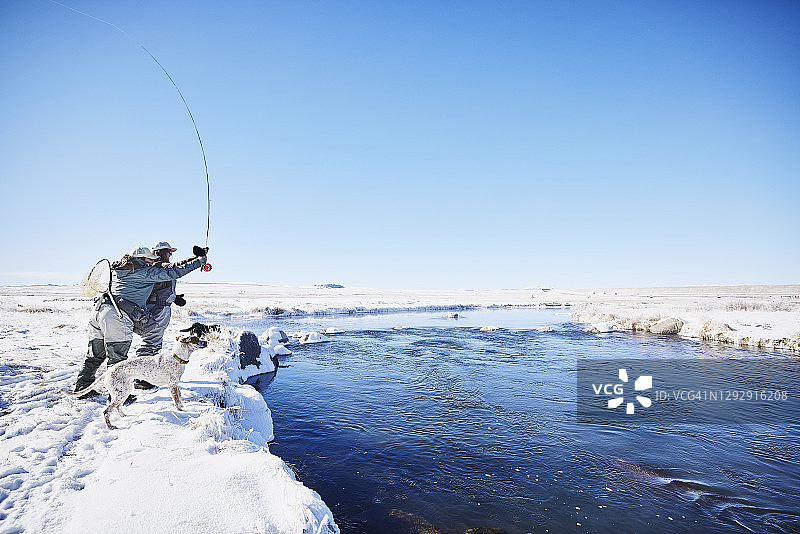 冬季清晨，女教师在河边教朋友飞蝇钓图片素材
