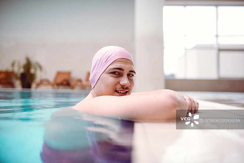 倚靠在游泳池边的年轻男人图片素材