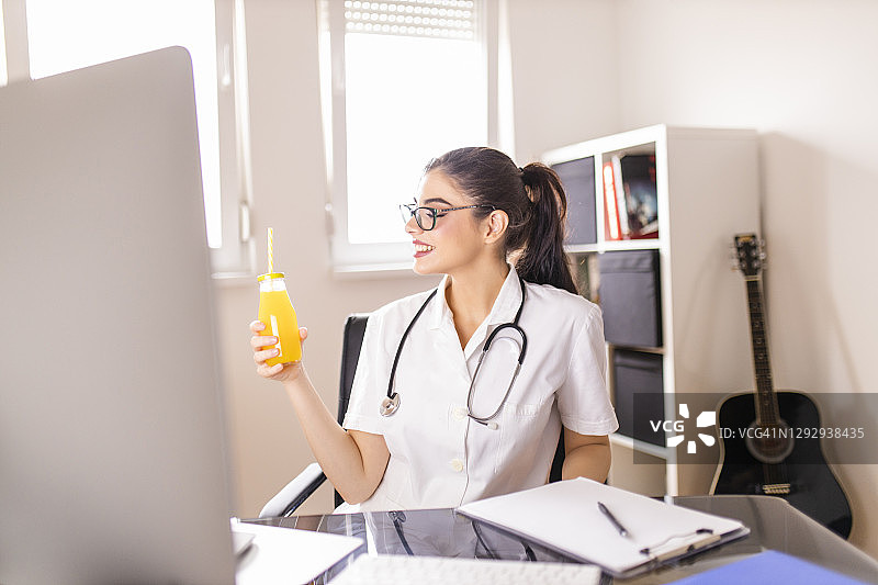 漂亮女医生在办公室工作并喝橙汁图片素材