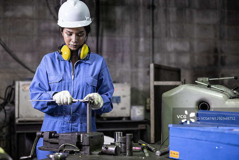美丽的亚洲女工程师在简陋的工厂里操作机械零件图片素材