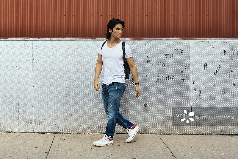 背着背包走在人行道上的男人图片素材