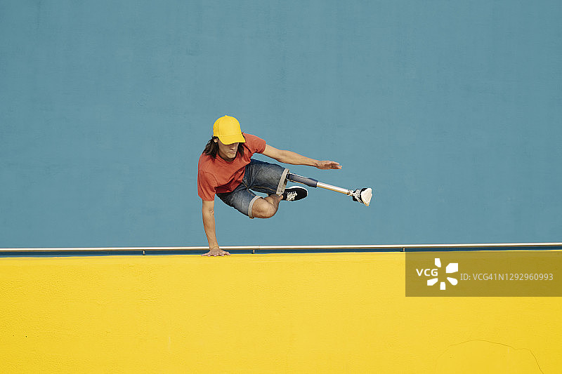 残疾运动员靠着彩色墙壁做倒立图片素材