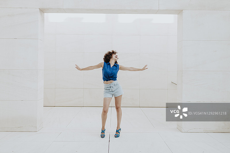 靠着瓷砖墙张开双臂的女人图片素材