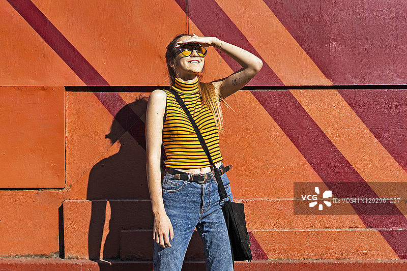 在墙边享受阳光的少女图片素材