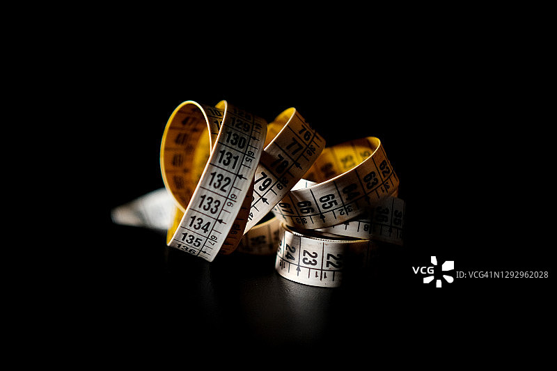 黑色背景上略有反光的黄色卷尺图片素材