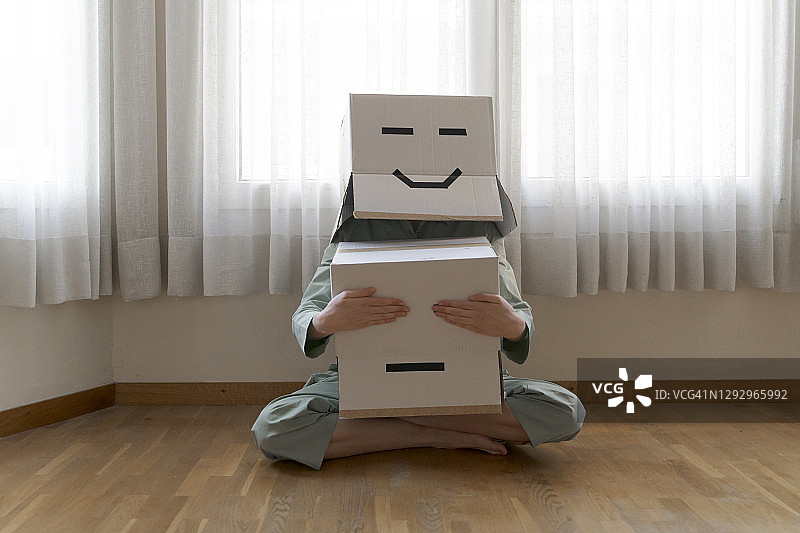 头上戴着笑脸纸箱、闭着眼睛的女人图片素材