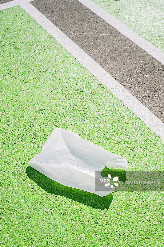 阳光明媚的日子里，绿色人行道上的塑料袋图片素材