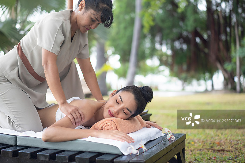 年轻女子在水疗中心享受颈部按摩图片素材