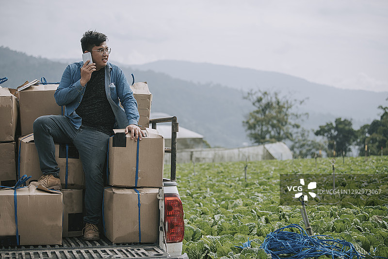 在皮卡车上用手机的亚洲男农民图片素材