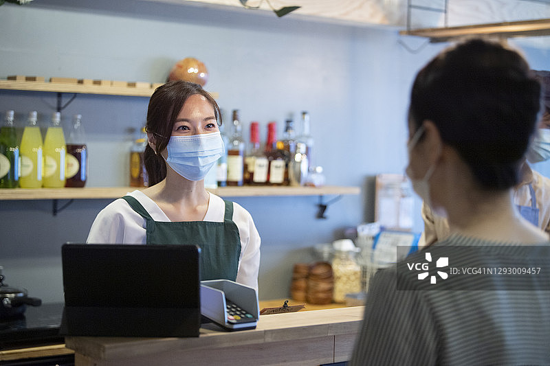 咖啡馆的女店员和女顾客愉快交谈图片素材