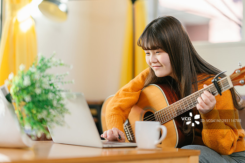 年轻女人居家在线学民谣吉他图片素材