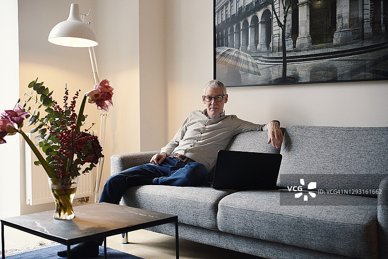 男人坐在沙发上用笔记本电脑图片素材
