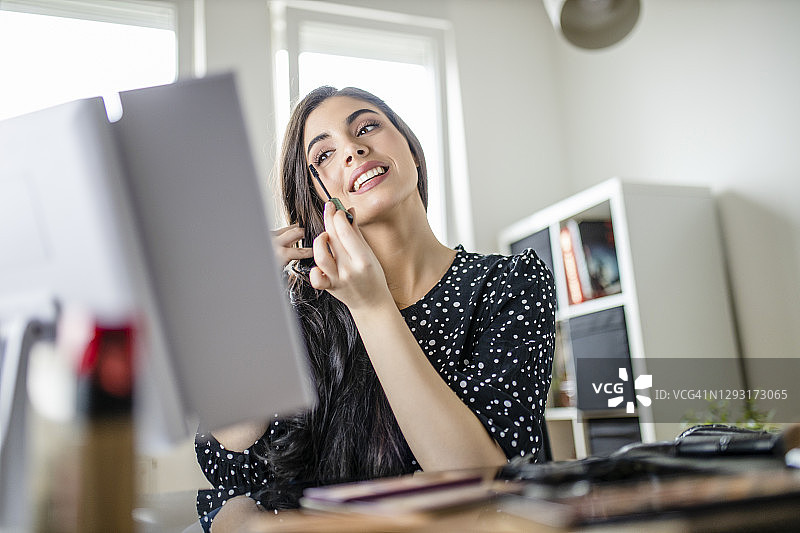 年轻女子在家庭办公室的镜子前化妆图片素材