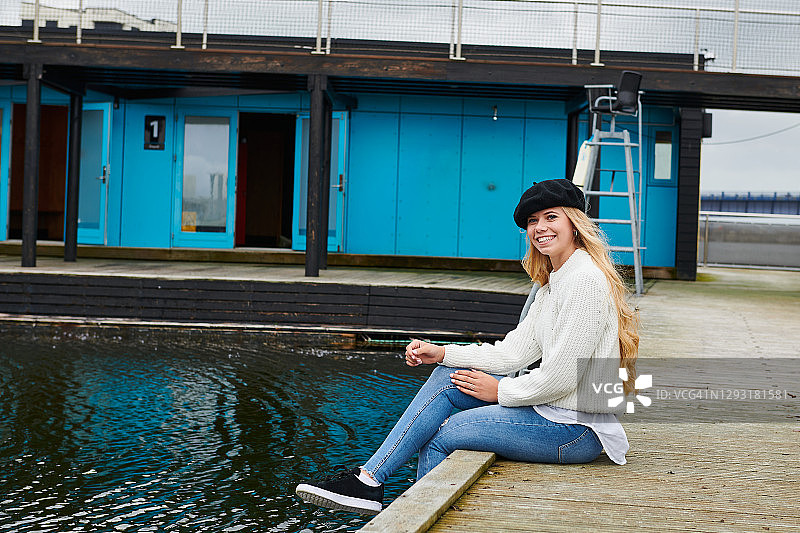戴贝雷帽的年轻女子在公共泳池边放松图片素材