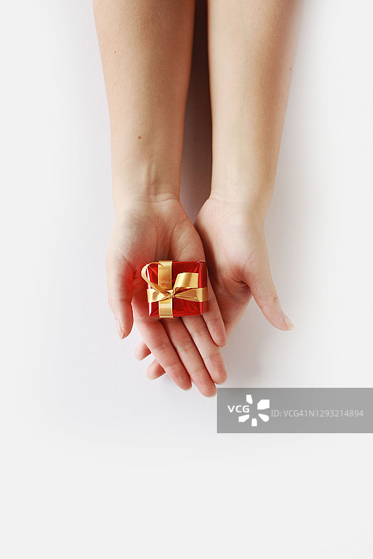 白色背景上拿着圣诞礼物的女人的手部特写图片素材