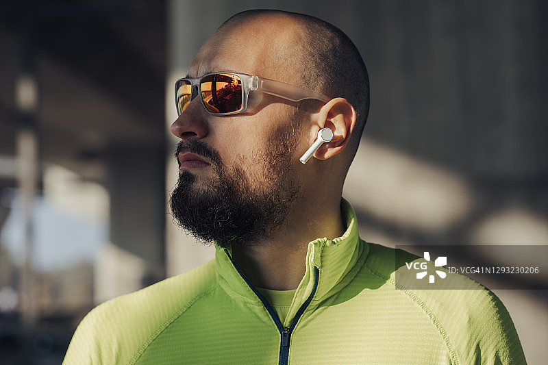 戴太阳镜和无线耳机穿着运动服的年轻男子图片素材