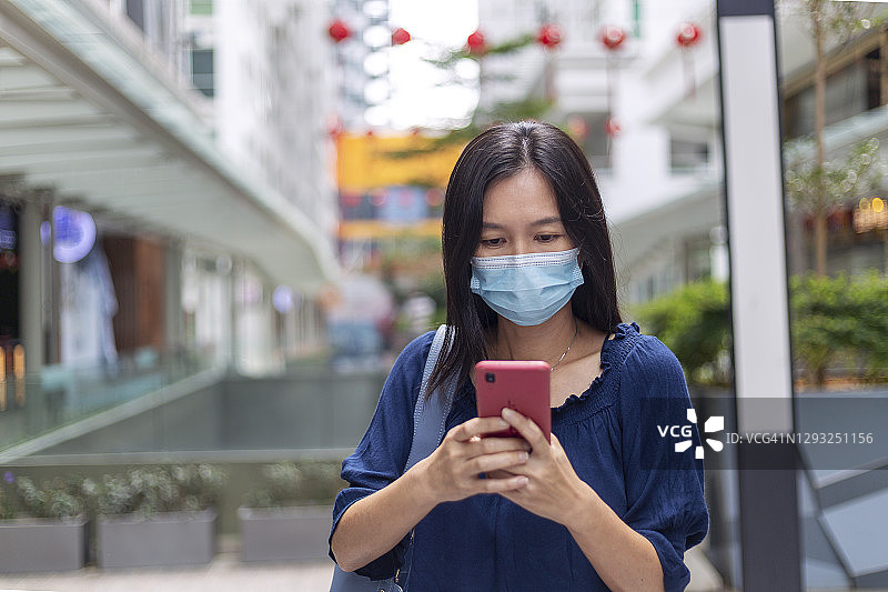 戴医用口罩在户外使用手机的女人图片素材