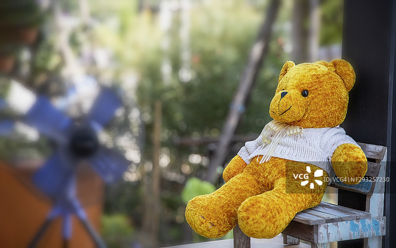 花园椅子上的黄色小熊玩偶图片素材