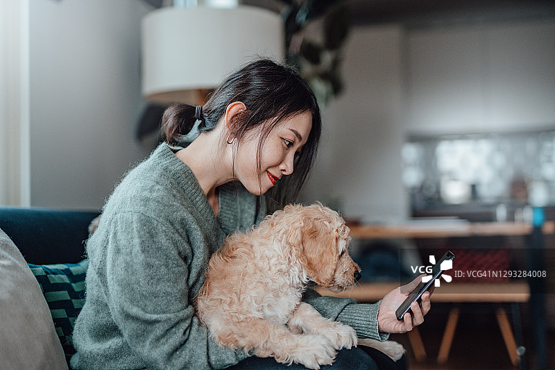 年轻女子用智能手机和她的狗自拍图片素材