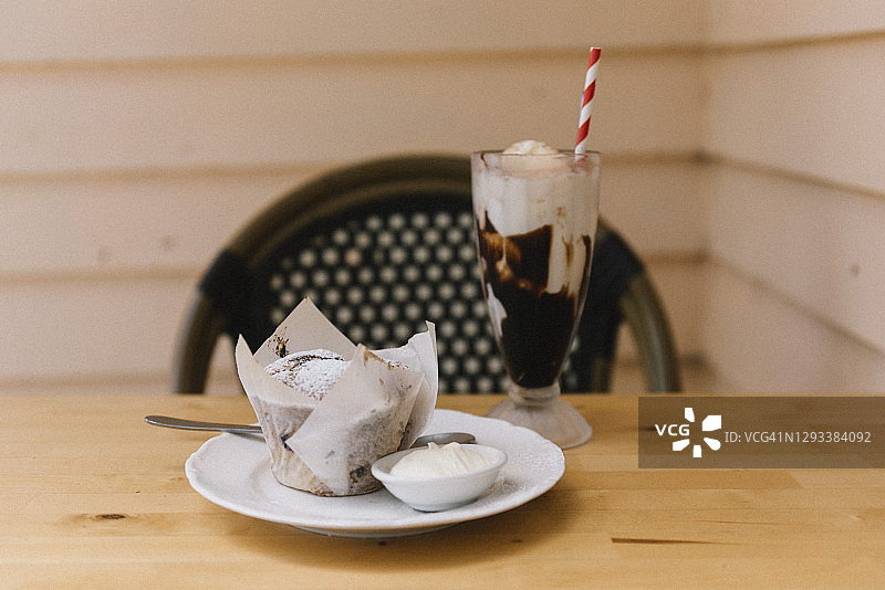 户外餐桌上的纸杯蛋糕、鲜奶油和冰巧克力饮品图片素材