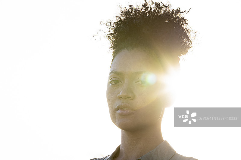 沐浴在日落光晕中的年轻女子侧面人像图片素材