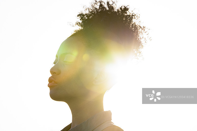 沐浴在日落光晕中的年轻女子侧面人像图片素材