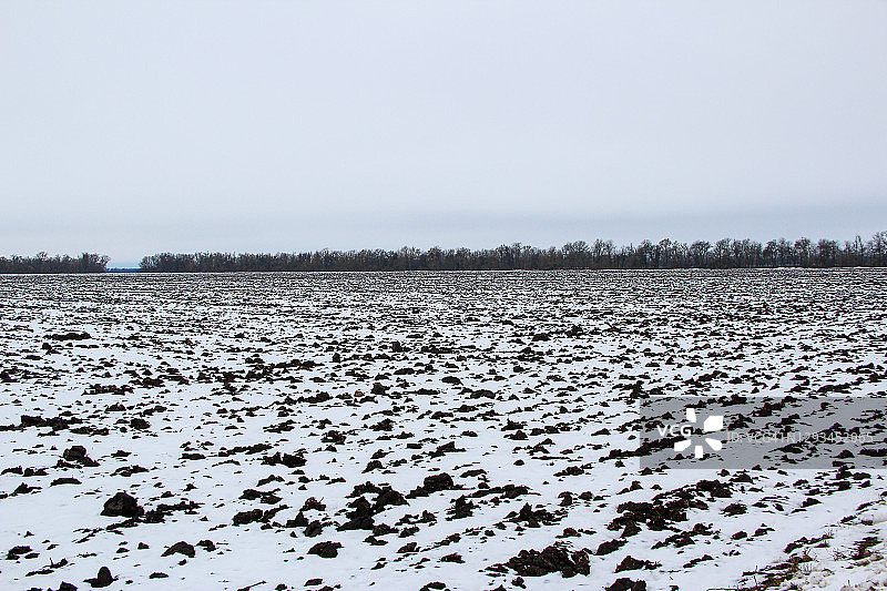 白雪覆盖的冬季农田和天空中的云彩图片素材