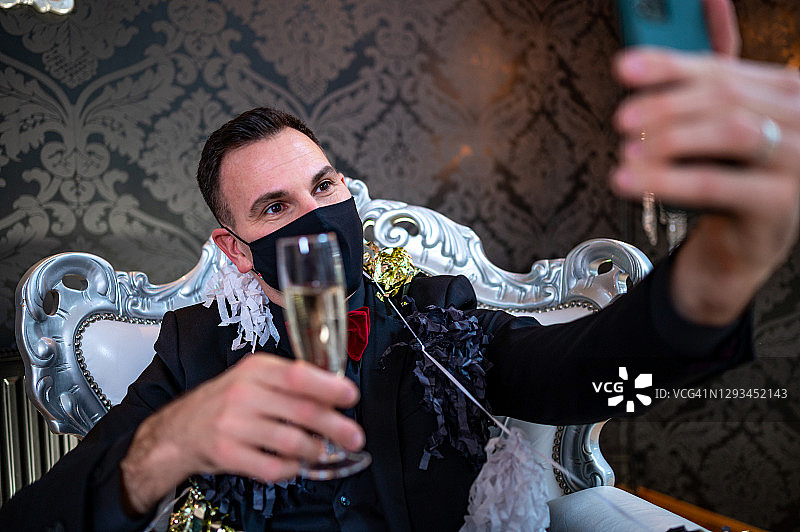手持香槟用手机自拍的英俊优雅男士图片素材