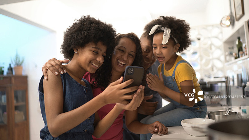 一家人在厨房里一起看手机或进行视频通话图片素材