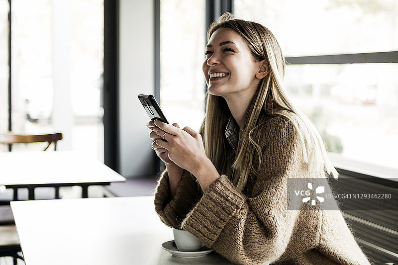 在餐厅喝咖啡和发短信的快乐女人图片素材
