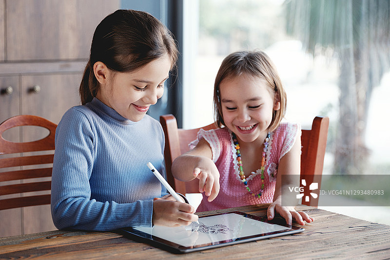 两个快乐的小女孩在家一起在数位板上绘画图片素材