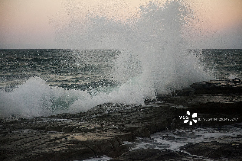 暮色时分，阳光海岸穆卢拉巴岩石架上的海浪，快速快门颗粒感照片图片素材