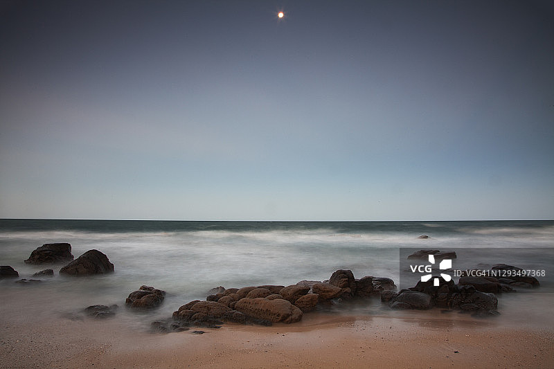 慢速快门拍摄的傍晚海滩岩石边波浪漩涡，澳大利亚昆士兰州阳光海岸穆卢拉巴图片素材