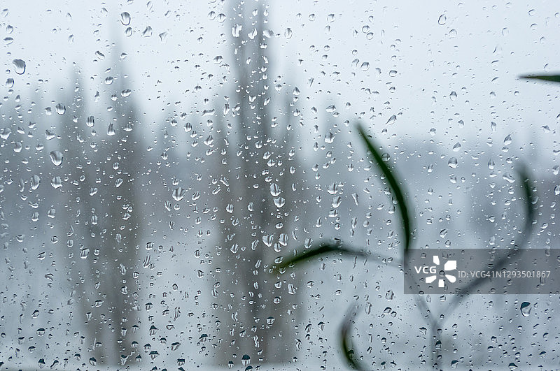 寒冷冬日窗户上的融雪和水滴凝结，窗外冬季景观特写图片素材