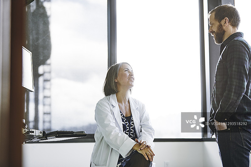 笑容满面的女医生在诊室与男病人交谈图片素材