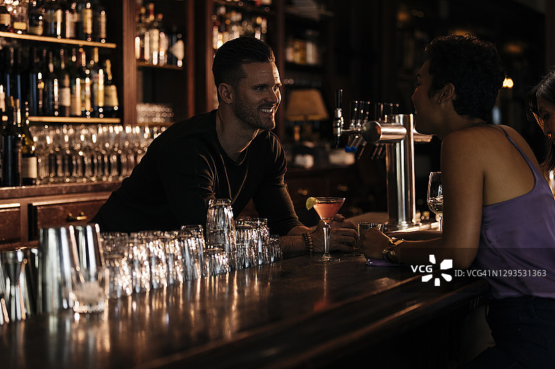 女人在餐厅与微笑的调酒师交谈图片素材