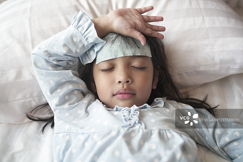 在医院接受病毒治疗的亚洲患儿。额头上贴着退热贴图片素材